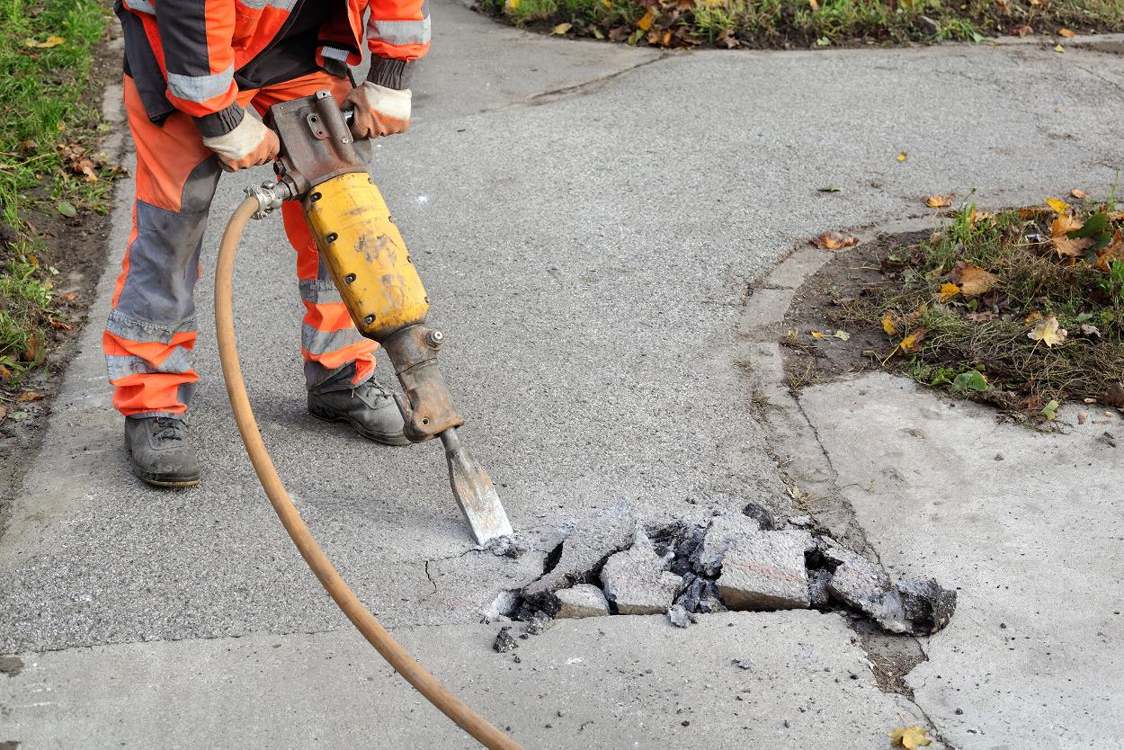 Construction worker breaking up asphalt pavement